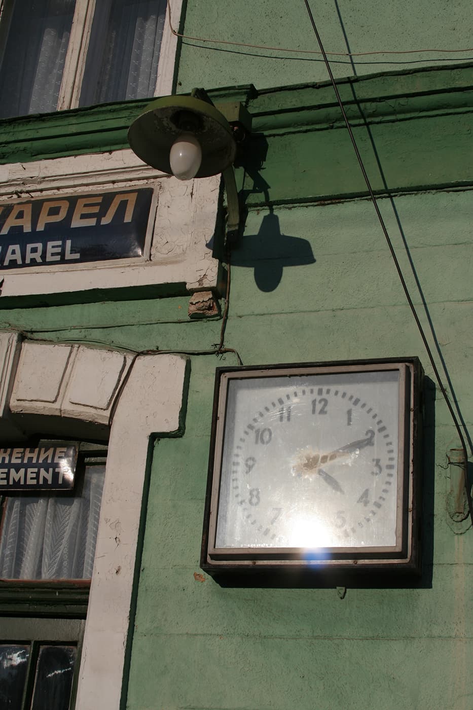 Facade of a train building featuring a clock and a hanging lamp above the entrance