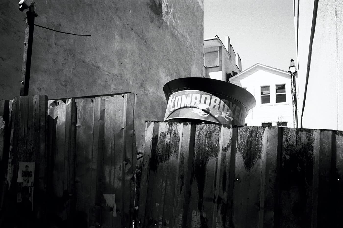A street boxing vending machine placed behind a fence in a small city courtyard