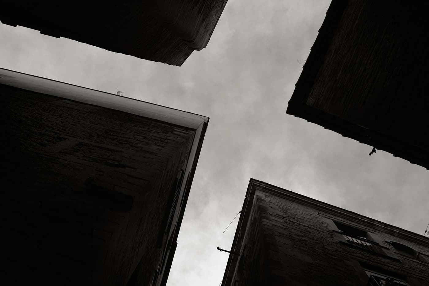 Upward view of a crossroad illusion created by four building rooftops forming a cross shape against the sky