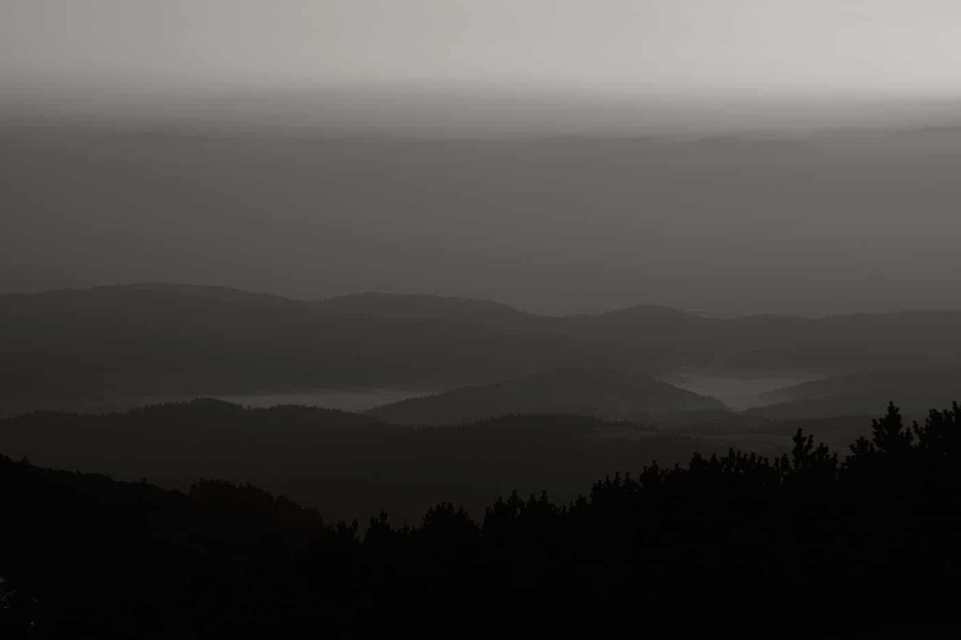 Early sunrise over mountain range with strange color gradients and shadow patterns across peaks