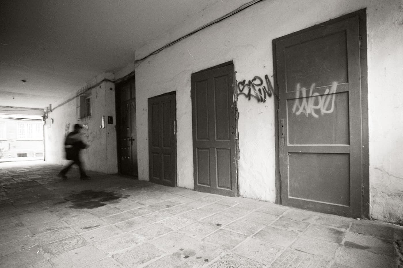A man approaching a door, with several other doors of different sizes next to it.