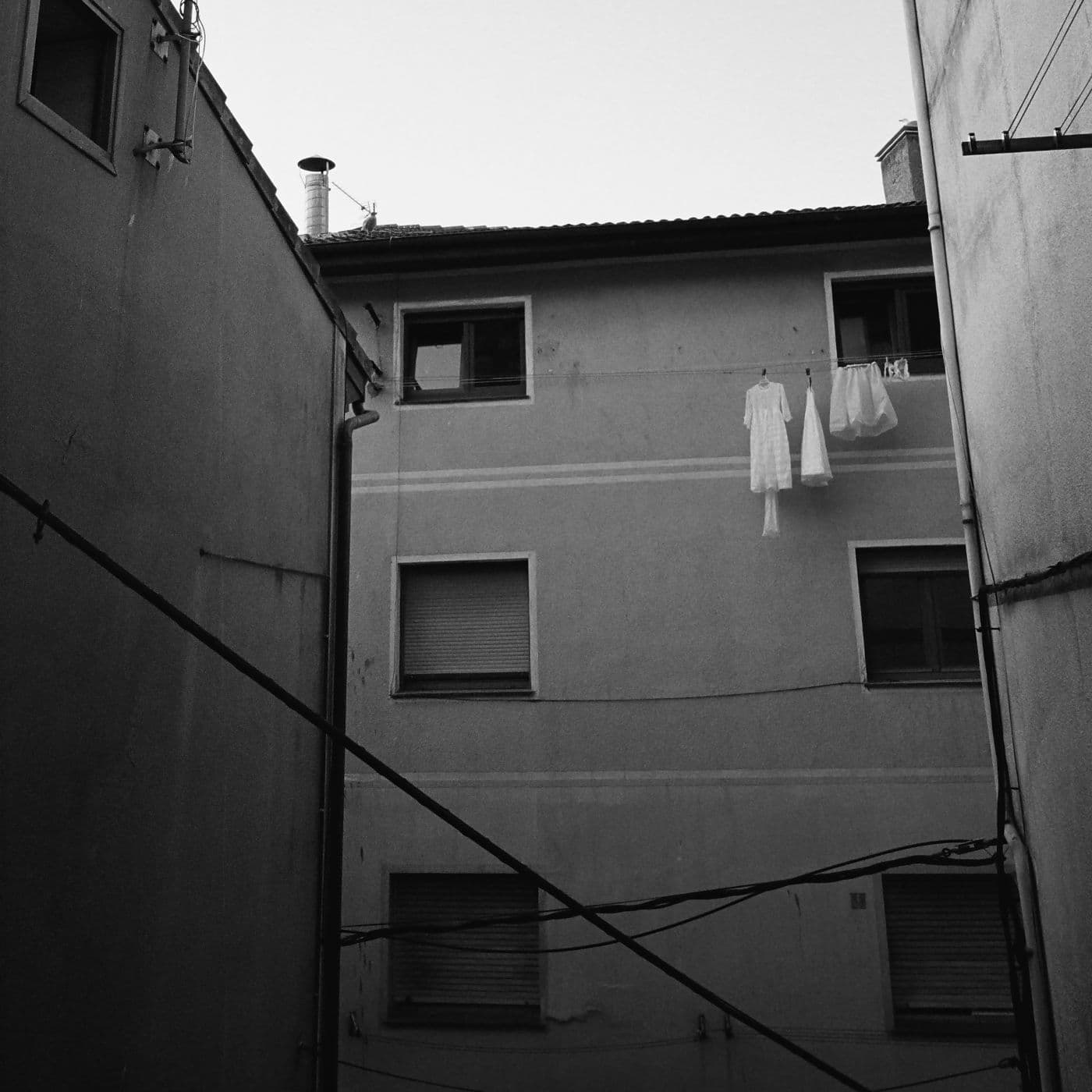A building with laundry wires and parts of a white dress hanging on them