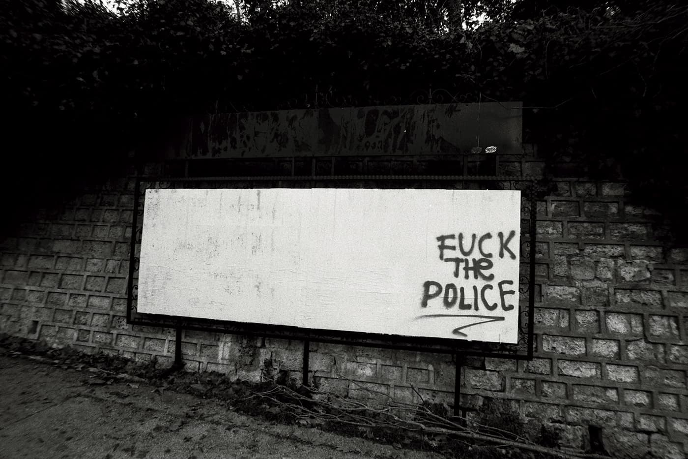 A large empty billboard with graffiti text on it reading "fuck the police"