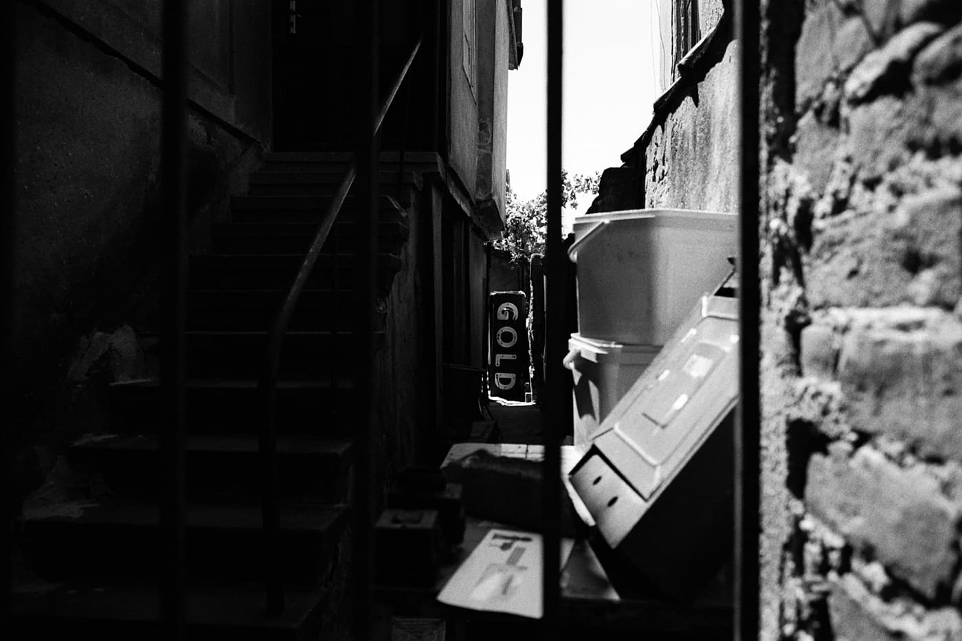 A city patio or small yard with scattered objects and a large sign reading GOLD