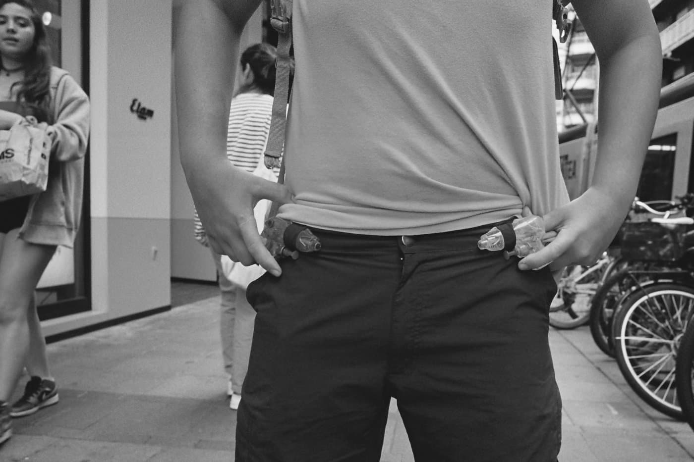 A person holding plastic pistols stuck into their trousers