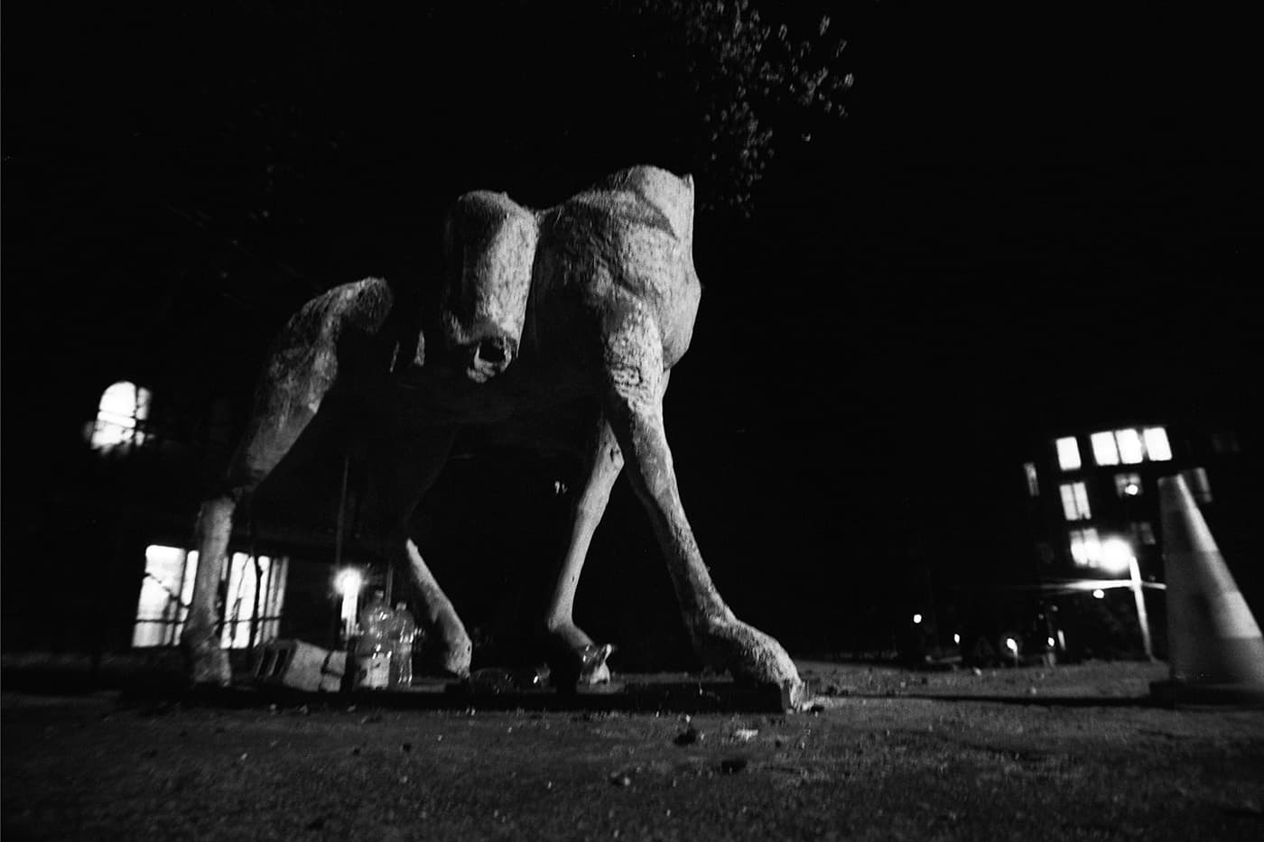 A horse sculpture with a road construction cone in front of it.