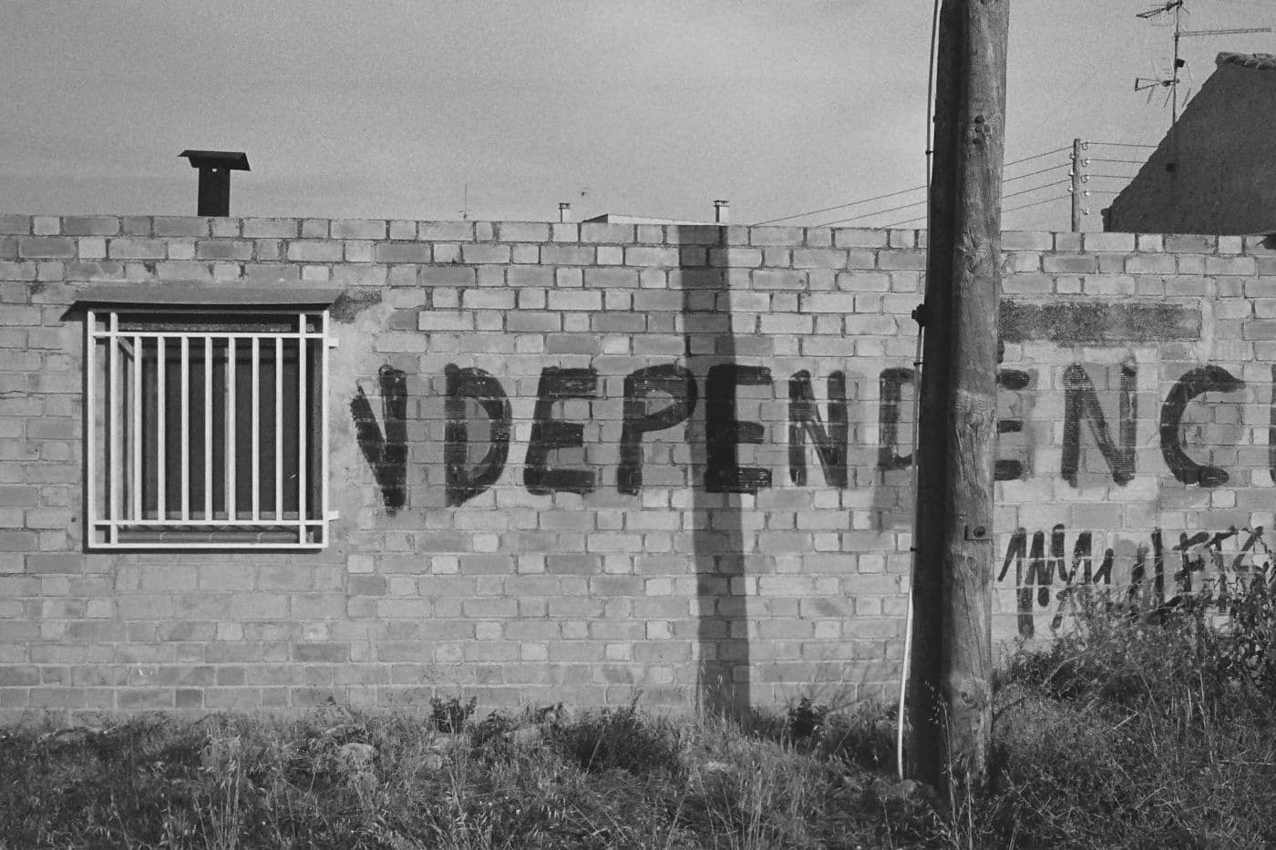 Graffiti on a wall reading independence, starting from a window with metal bars