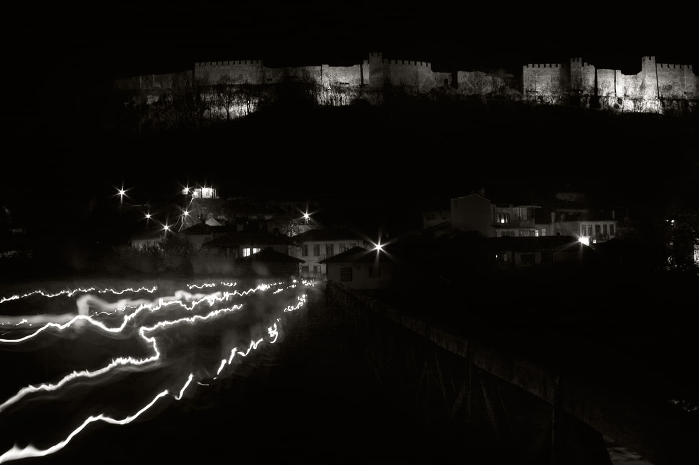 People walking away from a church at night during an easter christian event, with candles forming light trails in long exposure