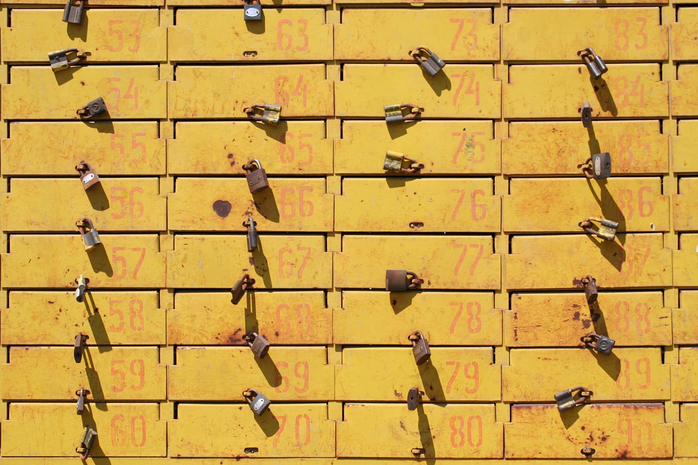 Old mailboxes painted yellow with numbered locked compartments and locks