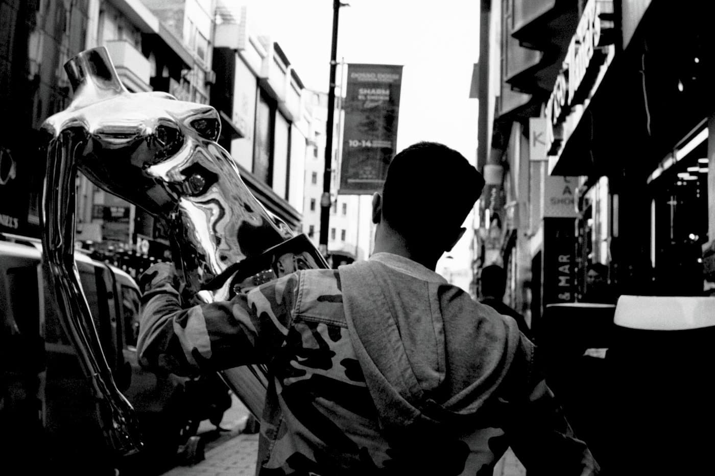 A man holding a metallic mannequin on a street