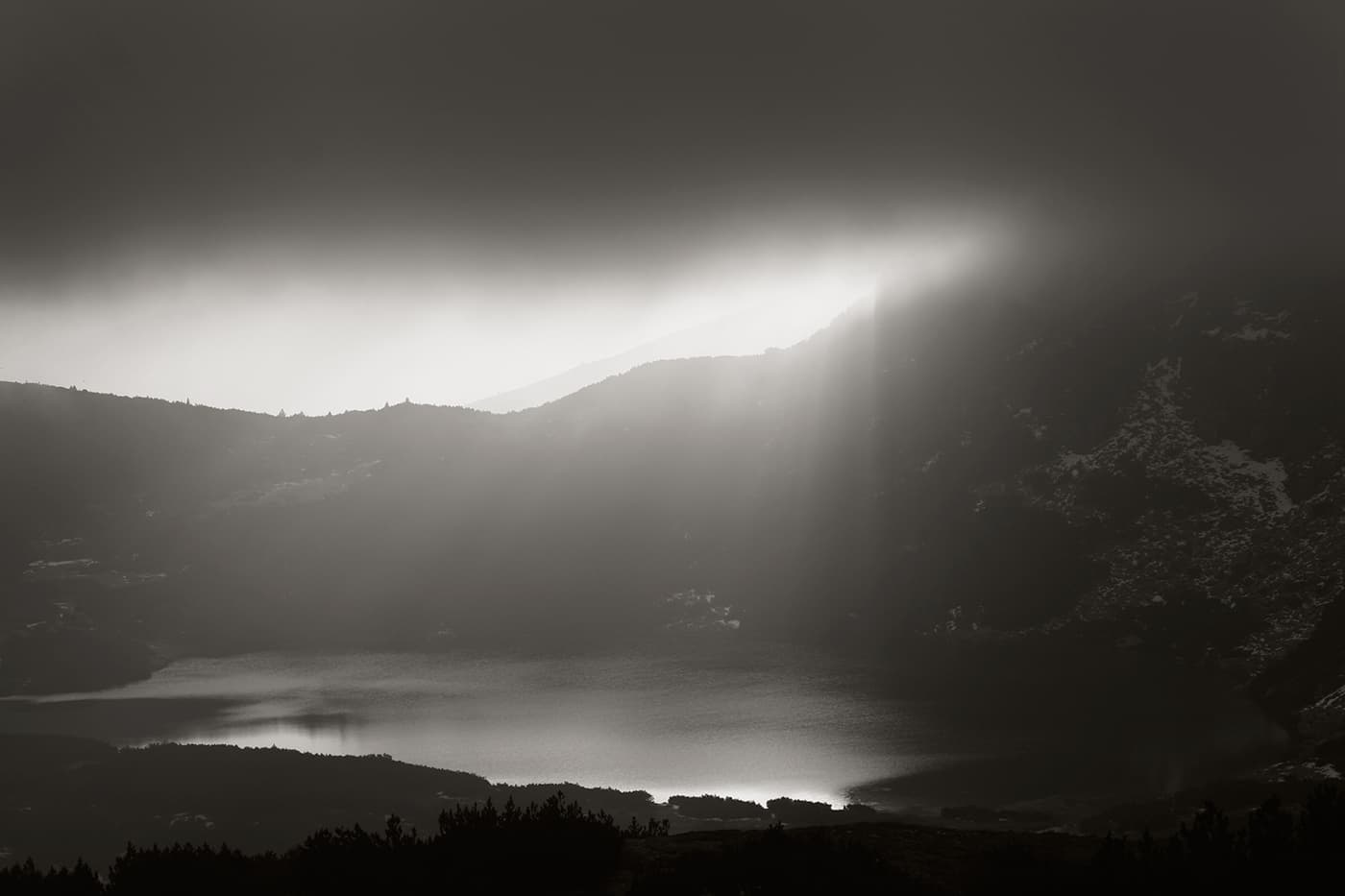 Unusual sunrise lighting over a mountain landscape with a lake and surrounding hills