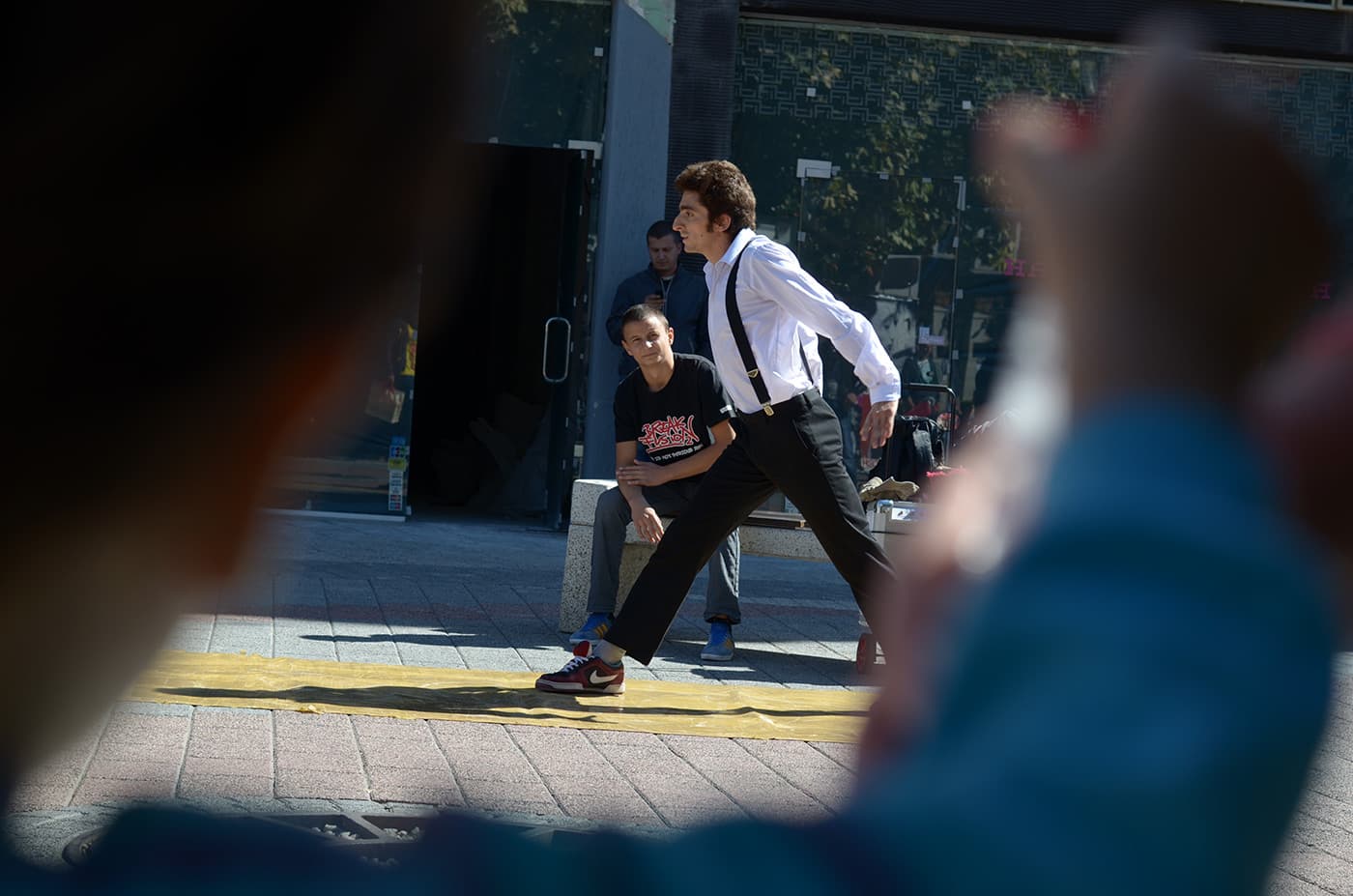 Street performer seen from behind a crowd of spectators gathered on the street during a public performance