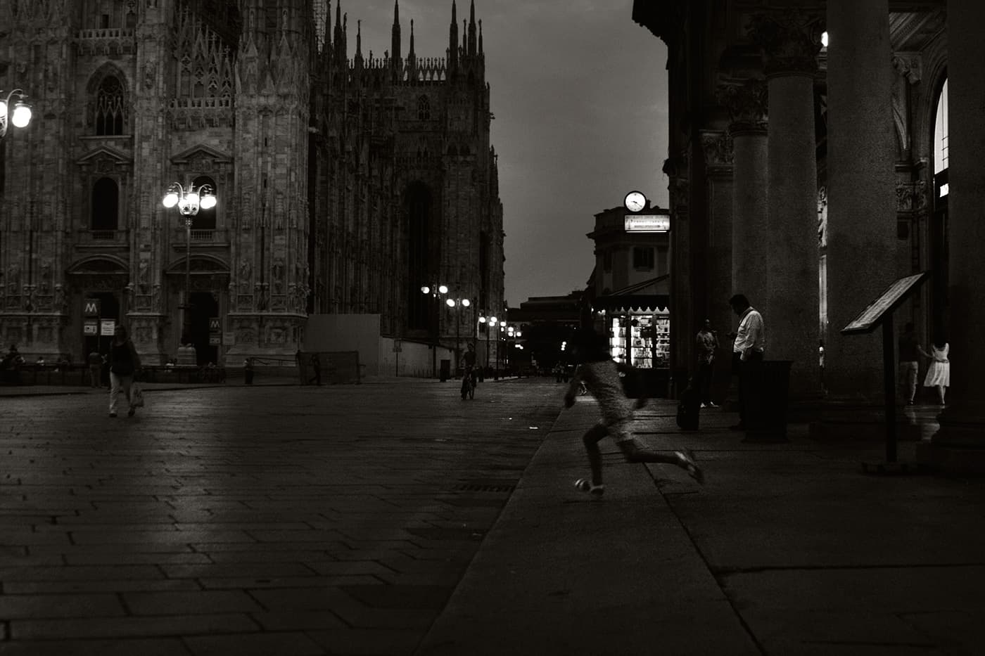Late evening scene in Milan near the cathedral with a running figure captured in motion blur in the city center
