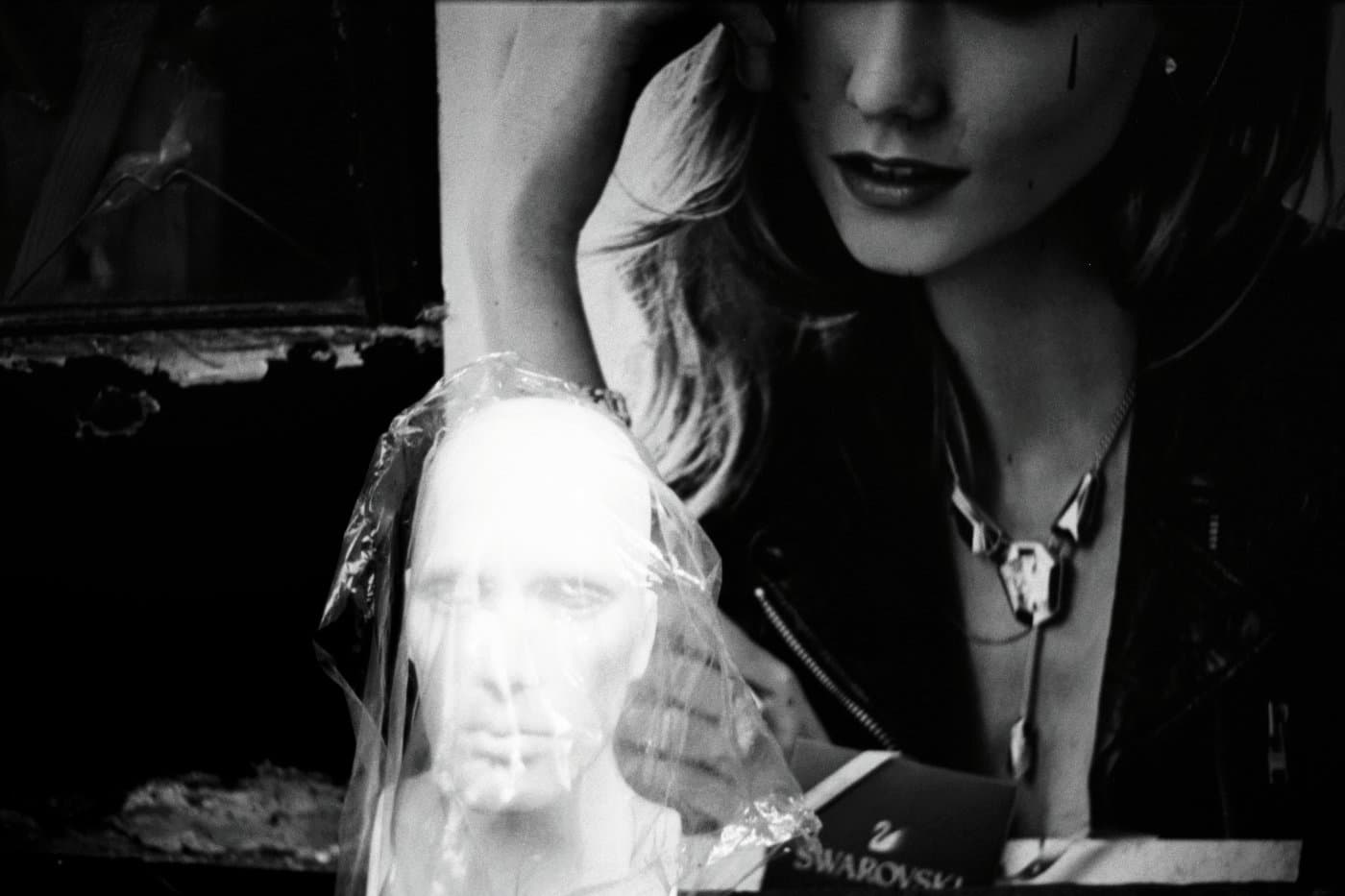 A woman looking at a small bust covered in plastic nylon