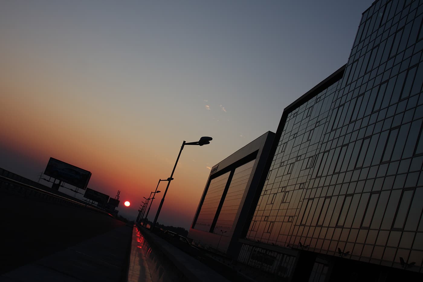 Sunrise urban landscape with a large corporate building on one side and a tilted perspective that makes the city appear to wrap and shift