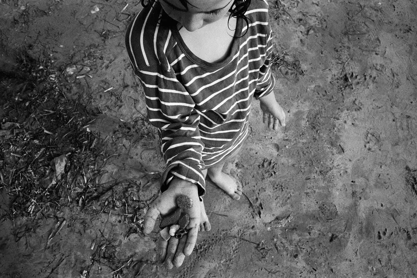Boy wearing a striped shirt holding rocks in his hand