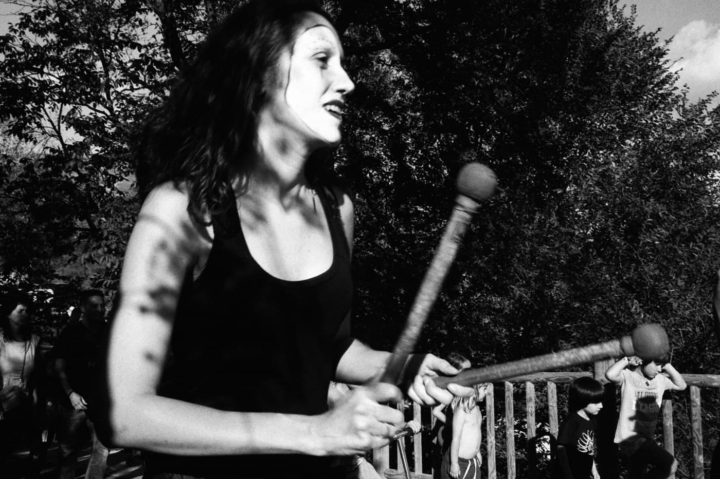 Close-up portrait of a drummer woman in a street batucada performance with painted mask-like face