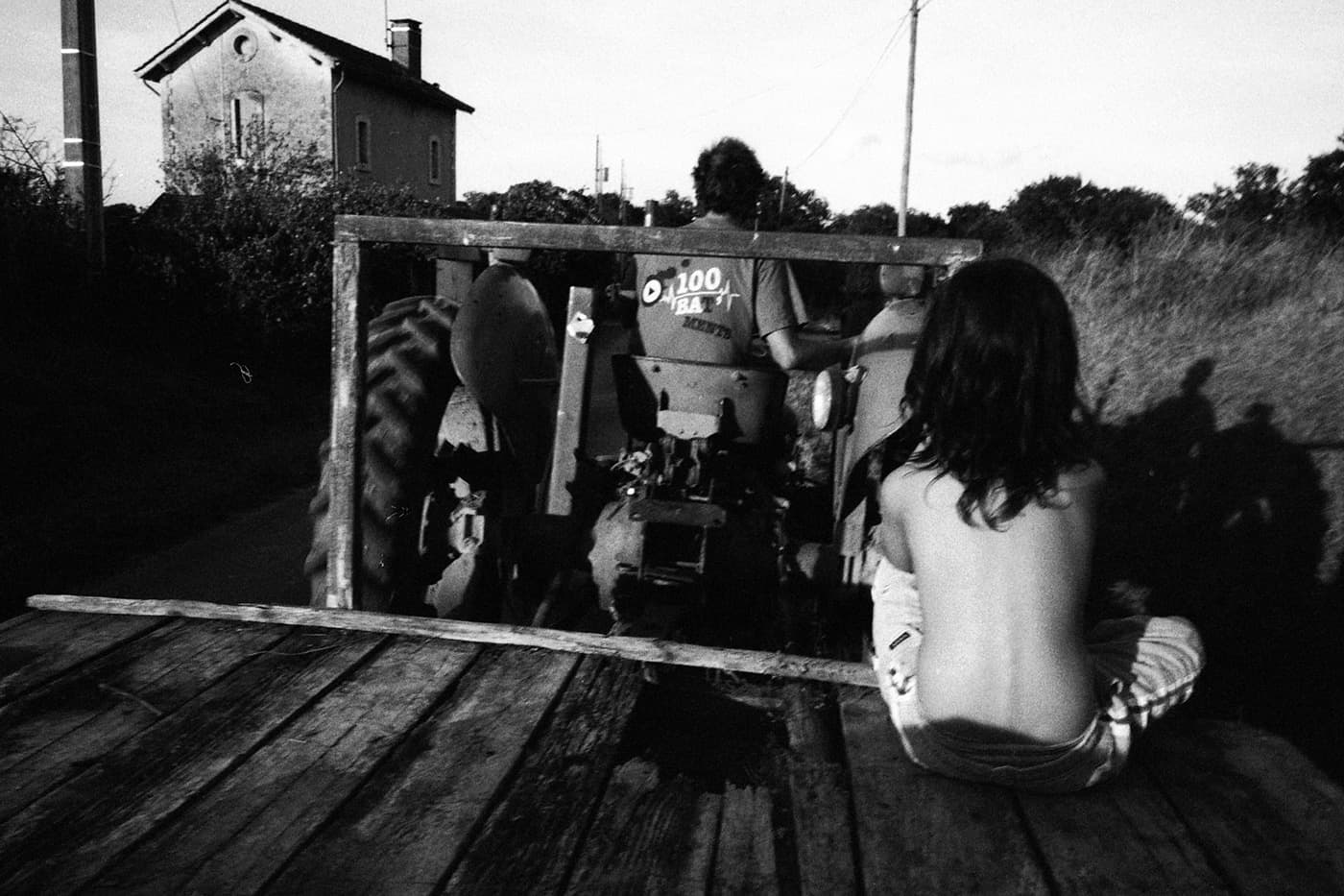 Kid sitting on a tractor trailer and a house in the background