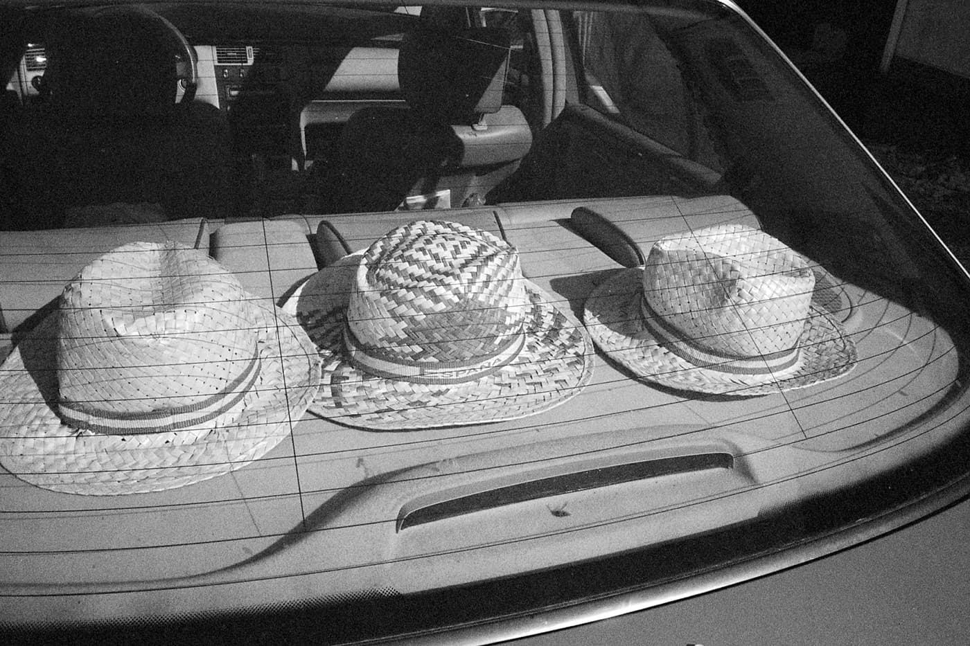 Three sun hats arranged in a row inside the back of a car