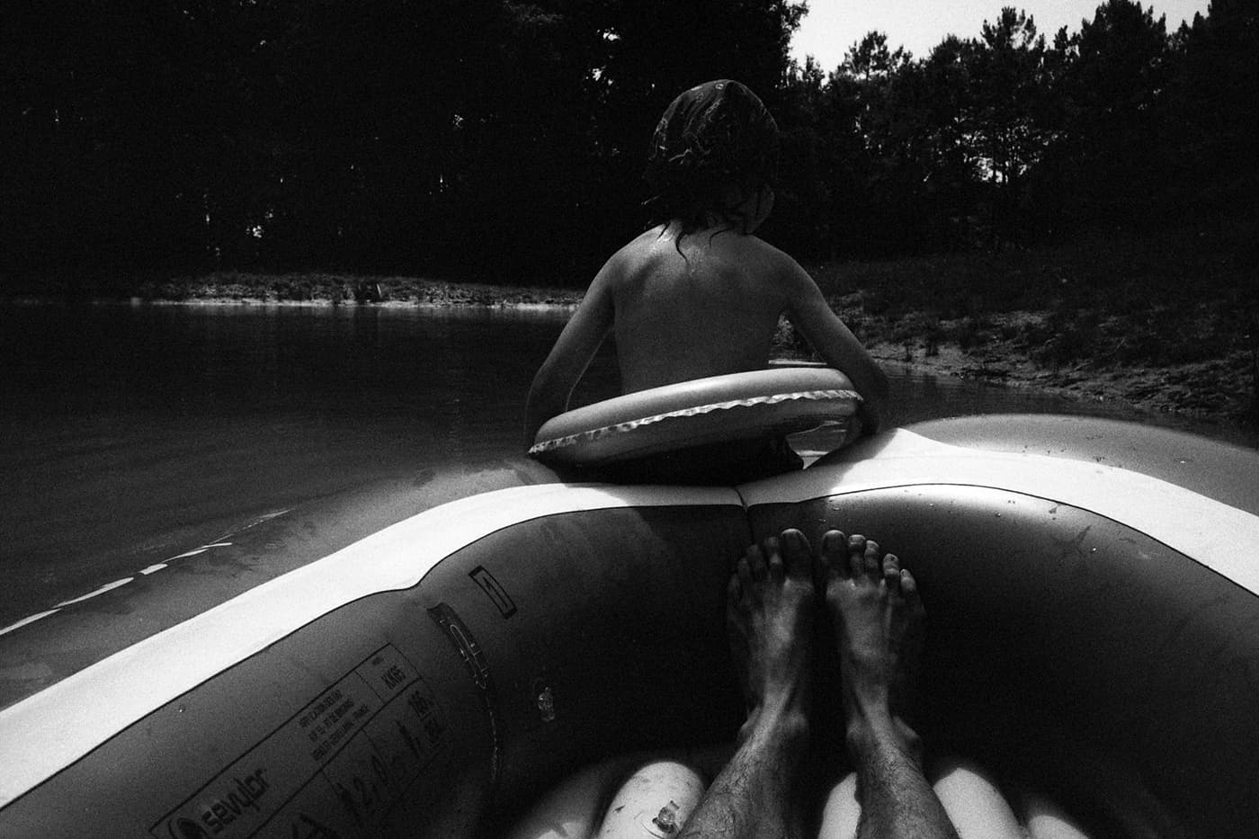Inflatable boat with a boy sitting on the edge with a flotation belt