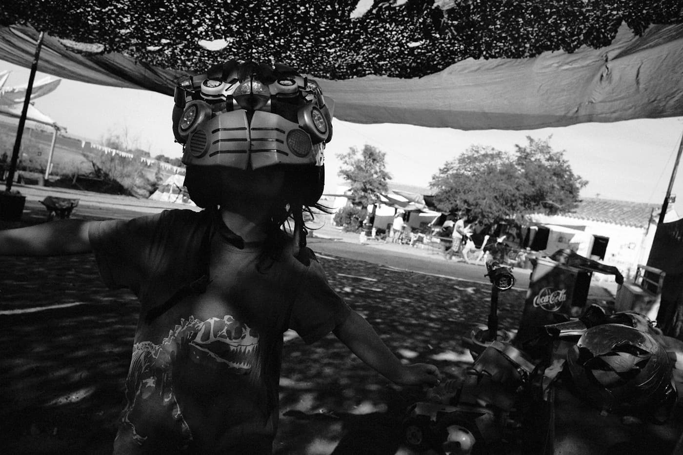 Kid with a transformer-style mask beneath a suspended fabric creating shade